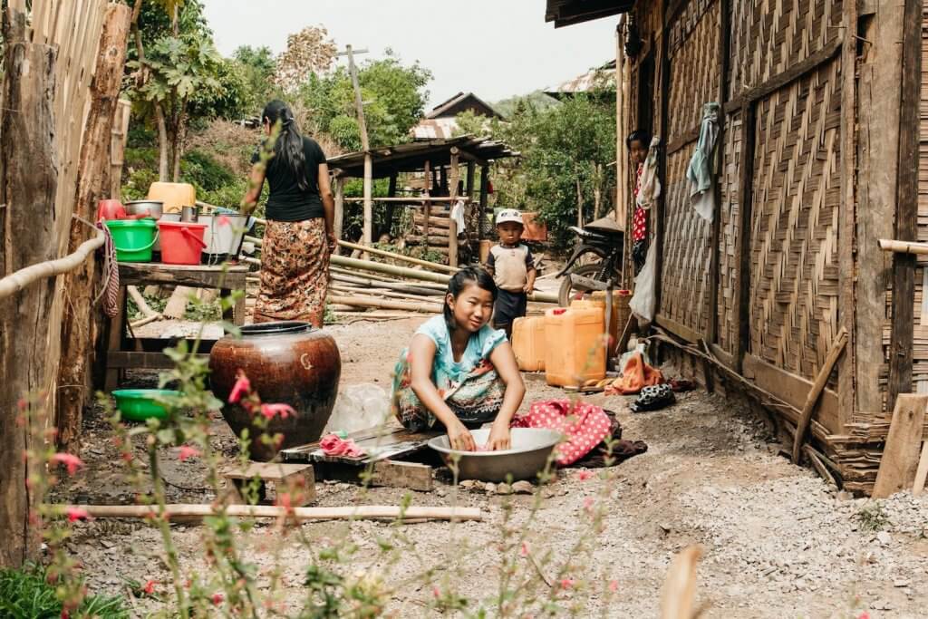 Photo of Myanmar villagers in the Shan State near Hsipaw washing clothing, while a child plays nearby. Photo by Ryan Brown of Lost Boy Memoirs, edited in Lightroom.