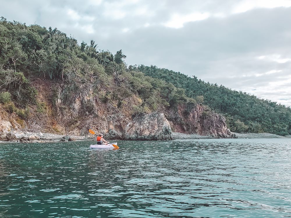 girl in purple kayak kayaking along rocky bays in hurricane hole