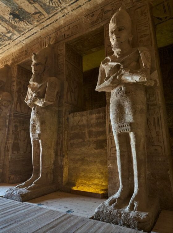 Two large statues in front of ancient hieroglyphics in Egypt.