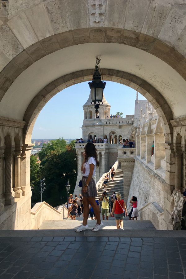 Woman in a skirt and t-shirt standing in the archway at Fisherman's Bastion in Budapest.