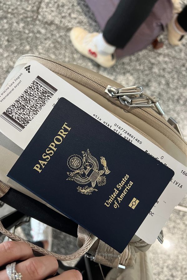 US passport sitting on top of a backpack with boarding passes sticking out of it.